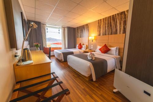 um quarto de hotel com duas camas e um gato sentado na cama em Lake Titicaca Hotel em Puno
