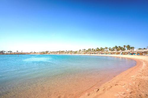 a beach with a group of umbrellas and the ocean at JAZ Palmariva Beach in Hurghada