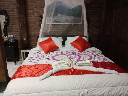 a bed with red and white sheets and red pillows at Villa Mak Cik in Yogyakarta