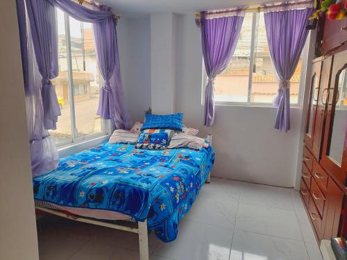 Cama pequeña en habitación con cortinas moradas en ENCALADA en Otavalo