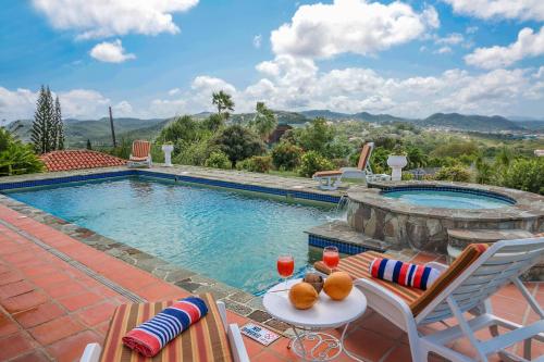 einen Pool mit Stühlen, einem Tisch und einem Tisch in der Unterkunft Calypso Court - Private 1 bedroom villa with pool villa in Cap Estate