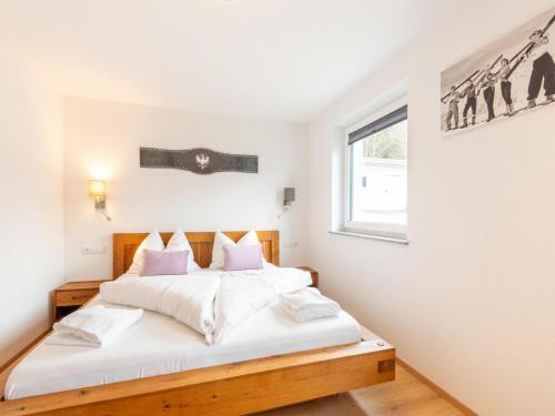 a bedroom with a bed with white sheets and a window at Thunhaus Apartments with ski-storage in Uderns