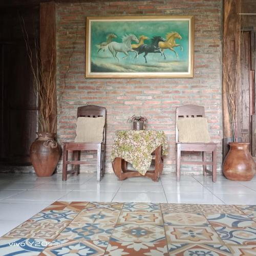 a room with a table and two chairs and a painting of horses at Villa Mak Cik in Yogyakarta