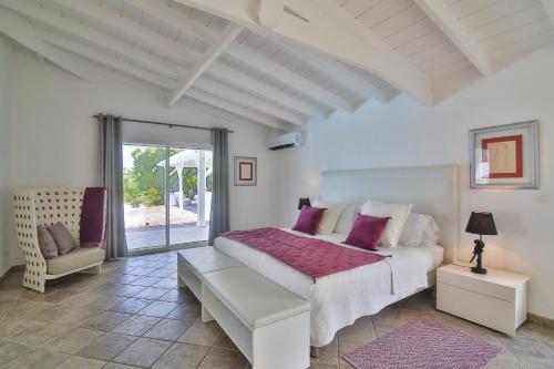 een witte slaapkamer met een bed en een stoel bij Luxury Vacation Villa 7 in Les Terres Basses