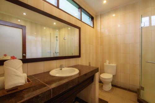 a bathroom with a sink and a toilet and a mirror at Champlung Sari Hotel and Spa Ubud in Ubud