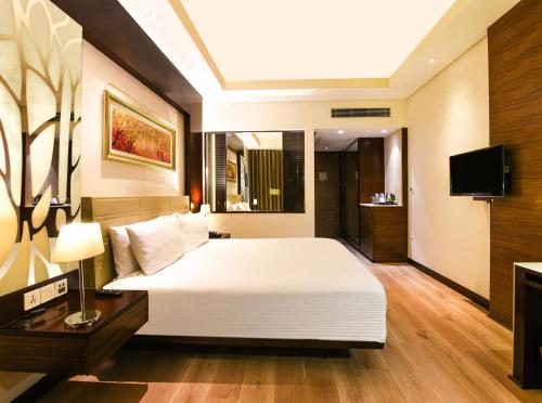 a bedroom with a large white bed and a television at DoubleTree by Hilton Gurugram Baani Square in Gurgaon