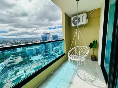 a balcony with a swinging chair and a large window at Luxury 1BR Apartment in Astria 706 in Tegucigalpa