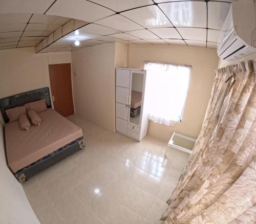 Habitación pequeña con cama y ventana en Omah Sidoarum Homestay Jogja, en Godean