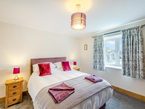 Un dormitorio con una cama con almohadas rojas y una ventana en Home Farm Cottage, en Sawley