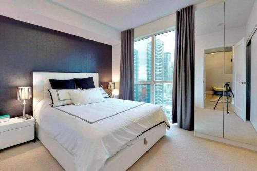 1 dormitorio con 1 cama blanca grande y ventana grande en Luxury 2 Bedroom Downtown en Toronto
