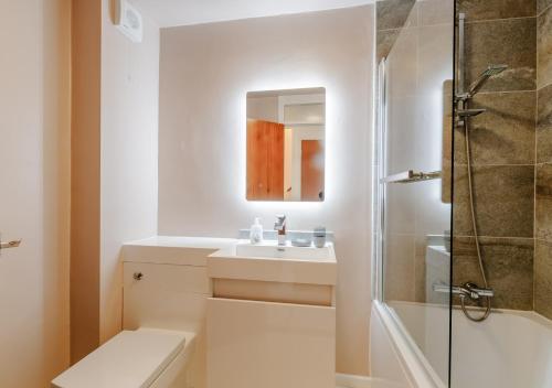 a white bathroom with a sink and a shower at By The Bay in Westgate-on-Sea