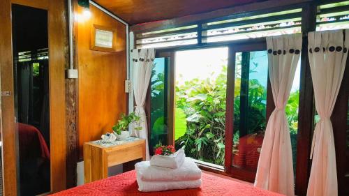 una habitación con una mesa roja con una ventana y una mesa con un jarrón en Pondok Pisces Balian, en Selemadeg