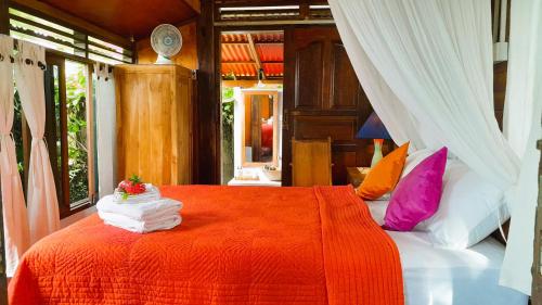 ein Schlafzimmer mit einem roten Bett mit Handtüchern darauf in der Unterkunft Pondok Pisces Balian in Selemadeg