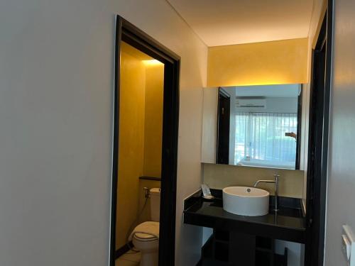 ein Badezimmer mit einem Waschbecken, einem WC und einem Spiegel in der Unterkunft โรงแรม ดิ โอวาเล่ย์ [The O Valley Boutique Hotel] 