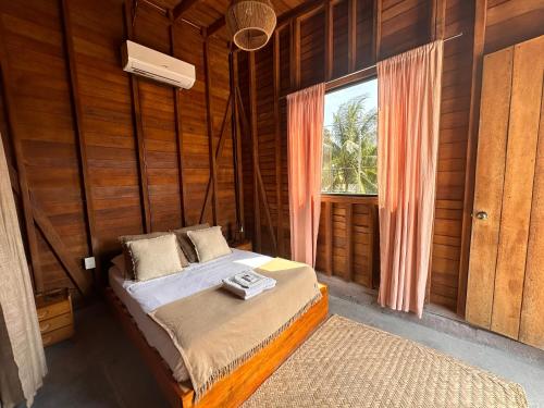 um quarto com uma cama num quarto com uma janela em Mapache Hostel & Camping em Holbox