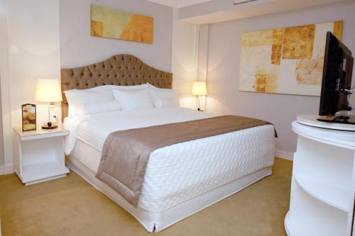a bedroom with a white bed and a television at Bristol International Guarulhos in Guarulhos