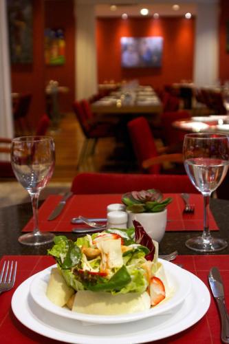 a plate of salad on a table with wine glasses at Bristol International Guarulhos in Guarulhos