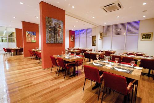 a restaurant with wooden tables and red chairs at Bristol International Guarulhos in Guarulhos
