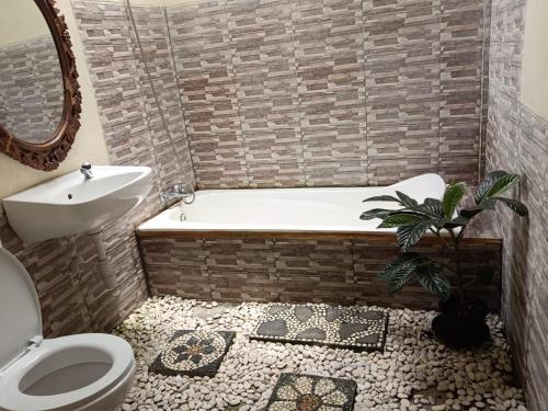 a bathroom with a tub and a toilet and a sink at Villa Mak Cik in Yogyakarta