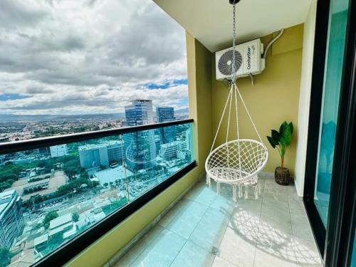 un balcón con una silla mecedora y una ventana grande en Luxury 1BR Apartment in Astria 706, en Tegucigalpa