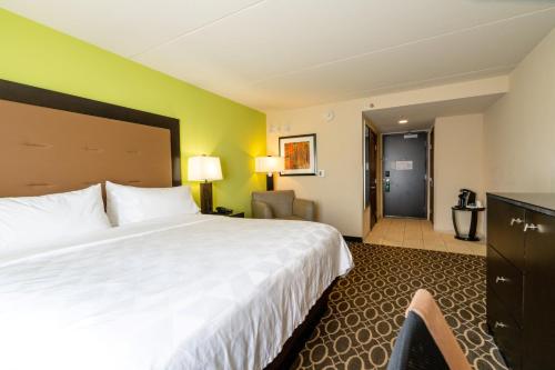a hotel room with a large bed and a chair at Holiday Inn Murfreesboro by IHG in Murfreesboro