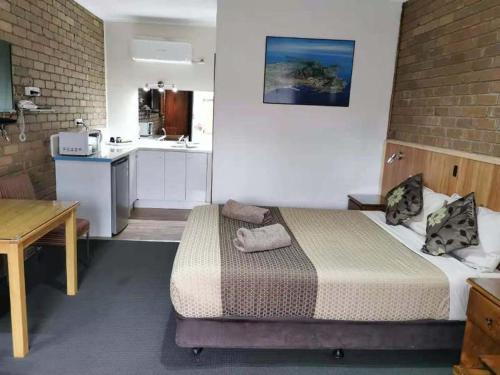 a small room with a bed and a kitchen at Peppinella Motel in Ballarat