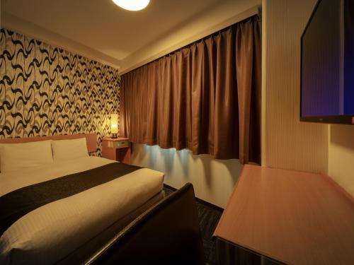 ein Hotelzimmer mit einem Bett und einem TV in der Unterkunft APA Hotel Maebashieki-Kita in Maebashi