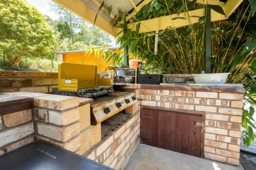 an outdoor kitchen with a grill on a brick wall at Tweed Hinterland Eco Cabin in Byangum