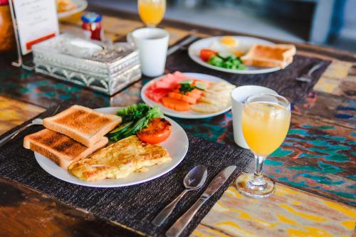een tafel met borden ontbijtproducten en een glas sinaasappelsap bij Casa Margarita Bali in Canggu