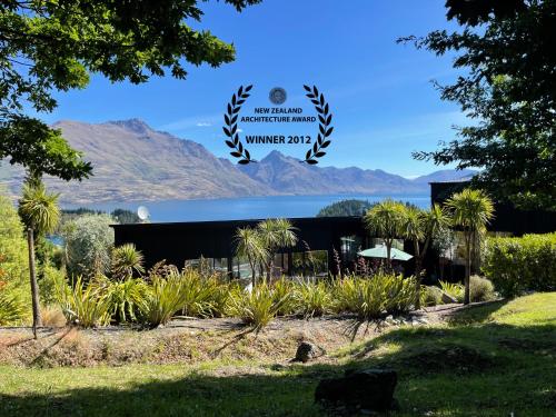 a building with a large sign with mountains in the background at Award-Winning Modern Retreat with Hot Tub & Views in Queenstown