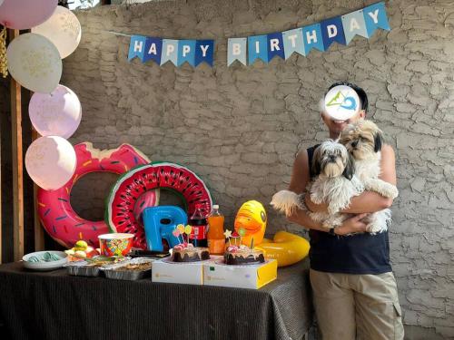 mężczyzna trzymający psa na przyjęciu urodzinowym w obiekcie Kubo house by the water in ELYU, Ba-ey Ad Shanom w mieście San Fernando