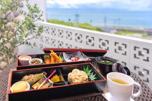 una mesa con dos bandejas de comida y una taza de café en Hotel Noir Blanc, en Shizuoka