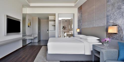 a bedroom with a white bed and a living room at Courtyard by Marriott Bhopal in Bhopal