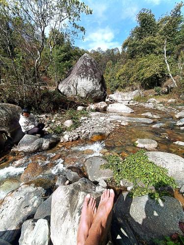 una persona sentada en algunas rocas en un río en Sabitri Homestay, en Panaoti