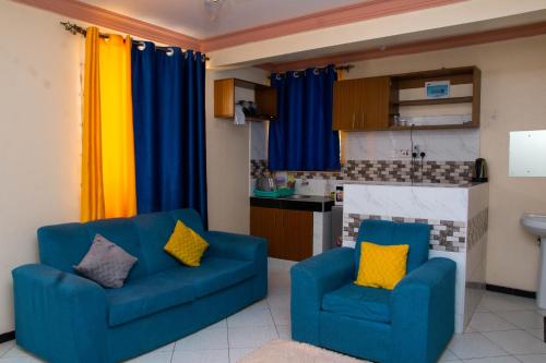 a living room with two blue chairs and a kitchen at Beach Box Dimash Apartments in Mombasa