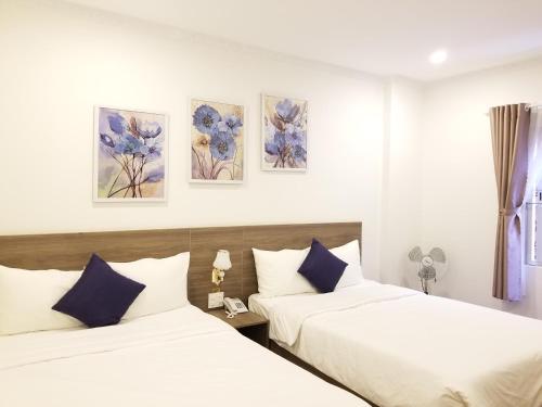 duas camas num quarto de hotel com flores azuis na parede em DẠ LAN HOTEL em Da Lat