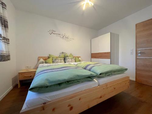 una camera da letto con un letto con cuscini verdi di Wohnen am Almufer - Ferienwohnung Straßmair a Grünau im Almtal
