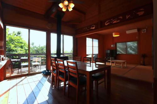 a dining room with a table and chairs and windows at Yuushin in Mifune