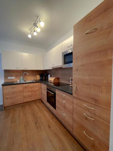 a large kitchen with wooden cabinets and a sink at Wohnen am Almufer - Ferienwohnung Straßmair in Grünau im Almtal