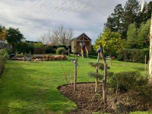a garden with a small tree and a log cabin at Le petit Radieux in Gémozac