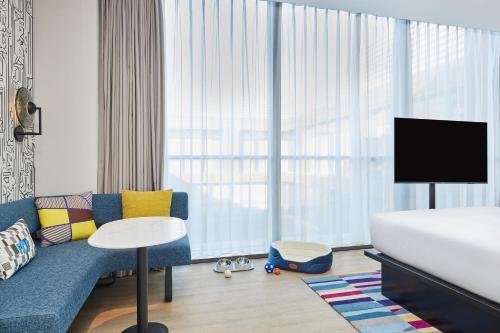a bedroom with a couch and a bed and a tv at Aloft Beijing Huairou in Huairou