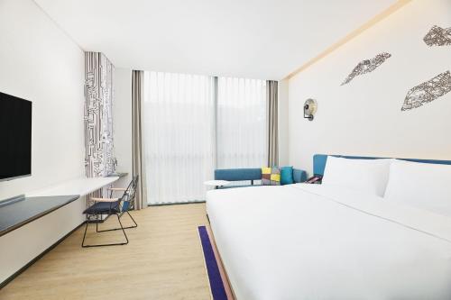a bedroom with a bed and a desk and a tv at Aloft Beijing Huairou in Huairou