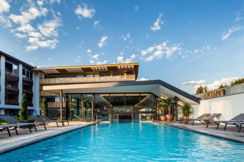 a swimming pool in front of a building at Hotel Petrus in Brunico