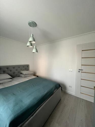 ein weißes Schlafzimmer mit einem Bett und zwei Leuchten in der Unterkunft Sweet Chic Home in Timişoara