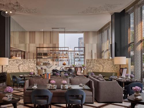 a hotel lobby with couches and tables and windows at Rosewood Bangkok in Bangkok