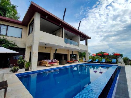 a house with a swimming pool in front of it at Villa Umbrella in Senggigi 