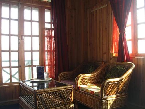 two wicker chairs and a table in a room with windows at Resort Sonar Tari in Kalimpong