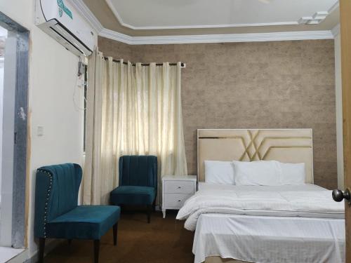 a bedroom with a bed and two blue chairs at Executive lounge in Lahore
