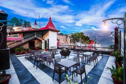 a patio with tables and chairs on a building at Hotel White Grand Shimla - IN CITY CENTRE - A Centrally AC Hotel in Shimla