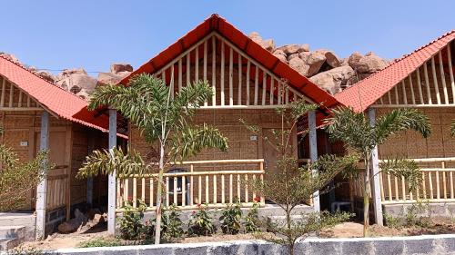 een huis met een hek en wat bomen en rotsen bij Osho's Organic Resort Hampi in Hampi